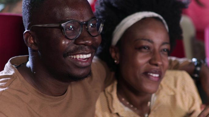 一对非裔美国夫妇看浪漫电影，在电影院里玩得很开心