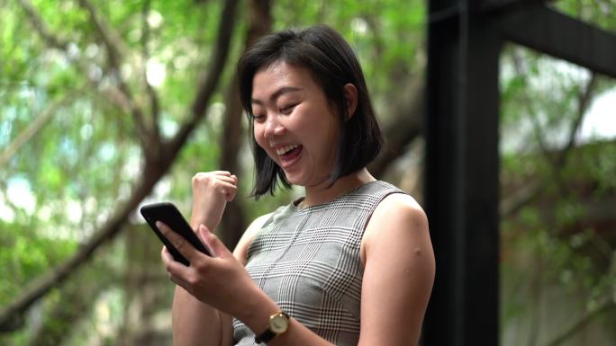 兴奋的亚洲女商人在智能手机上收到了好消息