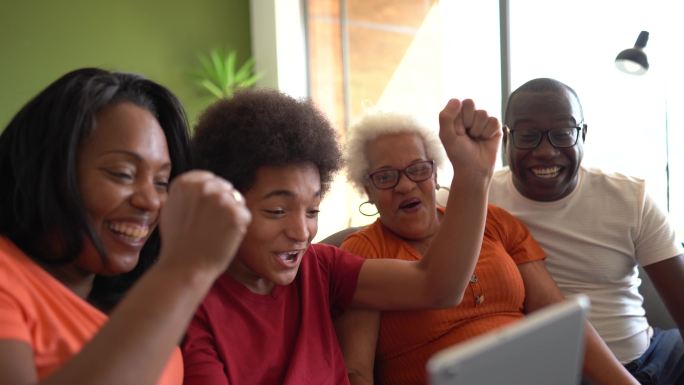 多代家庭在家里观看数字平板电脑时庆祝