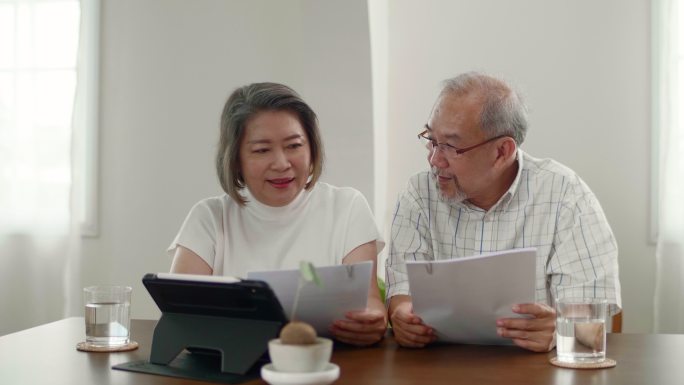 老年夫妇使用数字平板电脑技术管理家庭预算