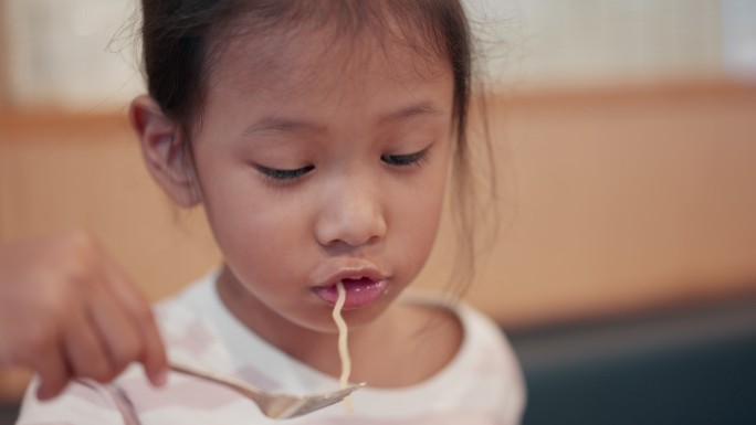 亚洲小女孩在餐厅吃日本面条的特写镜头