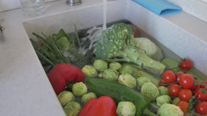 厨房水槽里装满了自来水，里面装满了各种各样的蔬菜