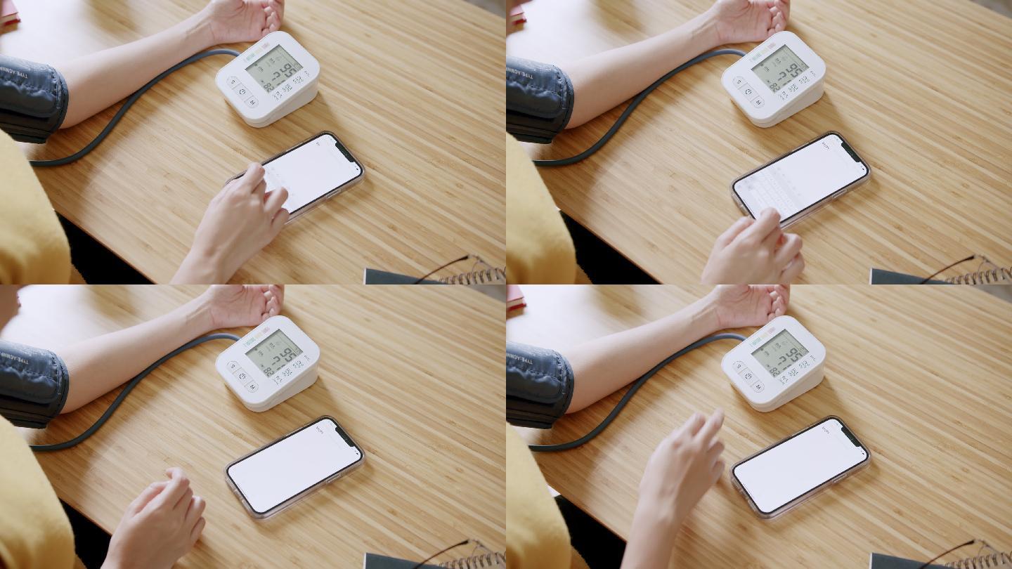 POV：亚洲女性自我血压和心率测量血压监护仪在家使用智能手机记录数据