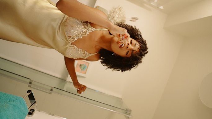 感觉棒极了。非洲裔女性享受早上的浴室常规，在镜子前玩得很开心。对着图像话筒唱歌