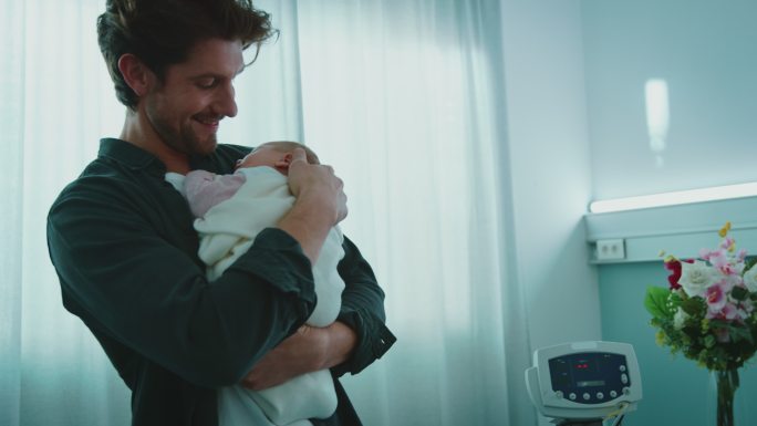 幸福的父亲在病房里抱着熟睡的新生儿
