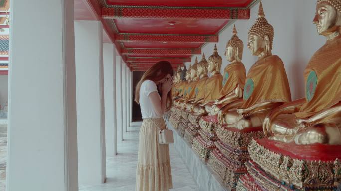 泰国曼谷，一位美丽的年轻女子在Wat Pho向佛陀致敬。地标/名胜古迹意外拍摄。