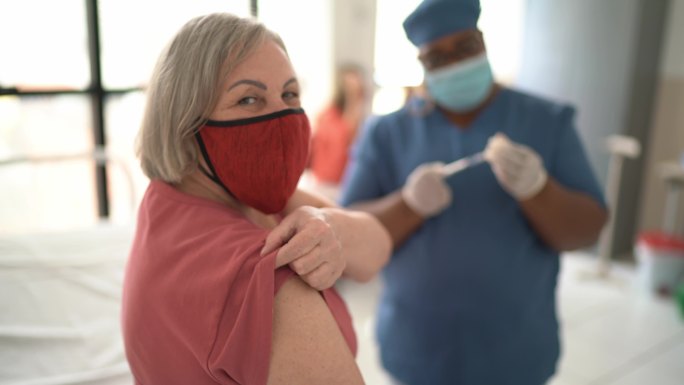 一位年长女性在接种疫苗前展示手臂的肖像-戴着口罩