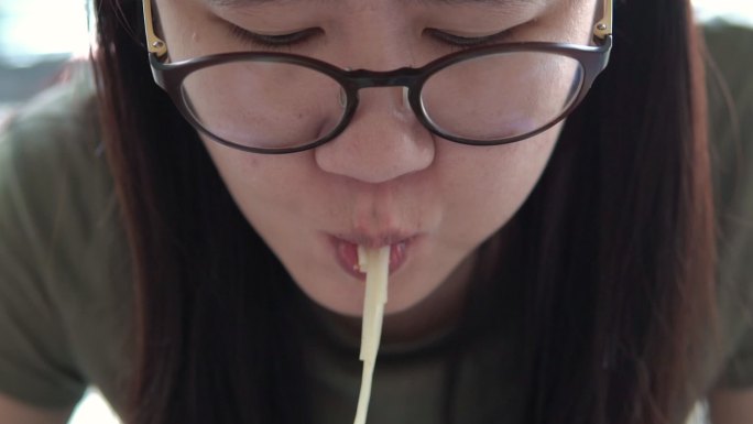 特写亚洲女性在当地餐厅吃面条。