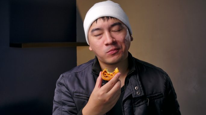 4K镜头青少年穿着冬衣，他拿着蛋挞，吃着美味的蛋挞。