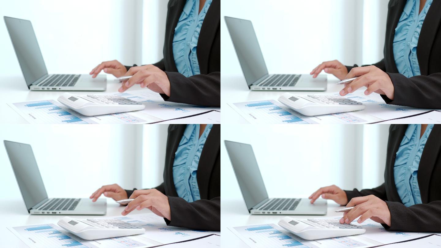 4K商业女性使用计算器在办公室笔记本电脑上处理财务和会计数据的视频片段