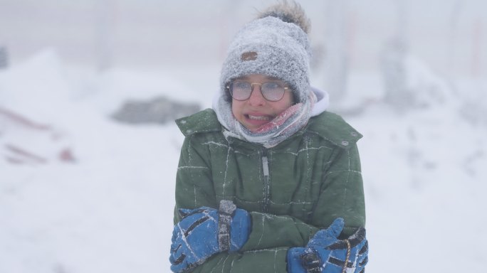一个十几岁的男孩的肖像，他在冬天的暴风雪中非常寒冷