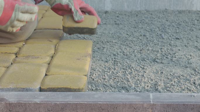 一名建筑工人的手正在人行道上铺设铺路石。