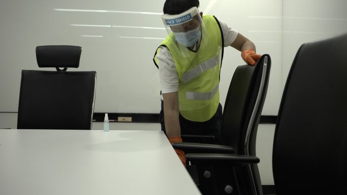冠状病毒2019冠状病毒疾病预防保洁员用抗菌消毒剂擦拭清洁桌，以杀死表面上的冠状病毒公共会议室把手上