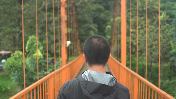 ้泰国男子旅行者走在橙色桥上前往万荣的坦昌洞