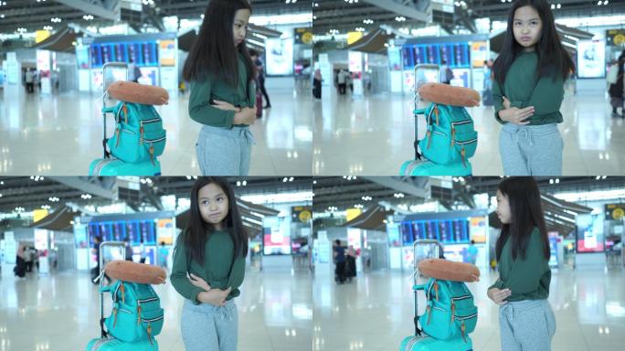 亚洲小女孩在机场的旅程，等待航班，面部表情，胃痛，患有膀胱炎，触摸腹部，感觉疼痛
