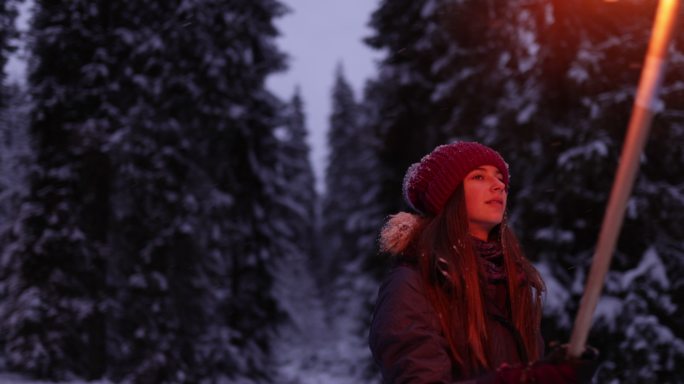 一个十几岁的女孩和她的家人拿着火把在冬天的森林里散步