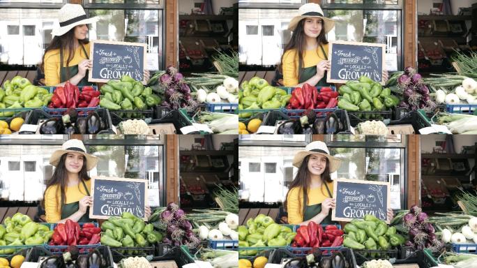 女蔬菜水果商站在商店旁边，举着招牌，周围是有机水果和蔬菜