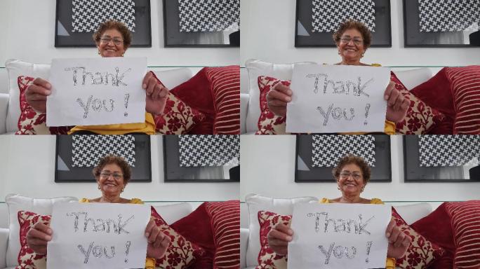 资深女士在视频通话中展示写有“谢谢”的论文-网络摄像头视角