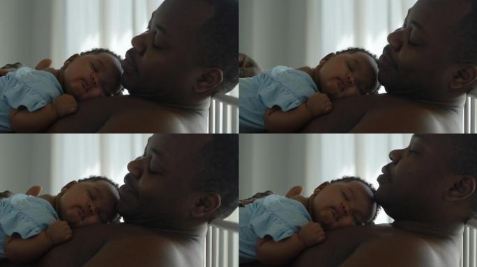 快乐的非洲父亲种族拥抱3个月大的新生儿，而她睡在他胸前的躯干上，时刻爸爸和宝宝在一起。父亲节概念。