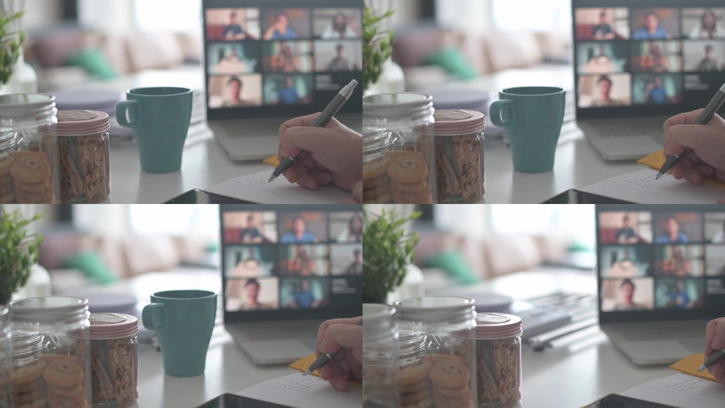 厨房柜台上带屏幕视频会议的笔记本电脑，带智能手机、记事本