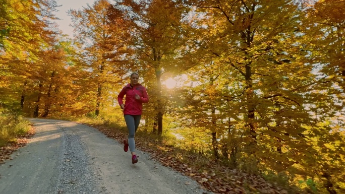 在阳光明媚的秋林中奔跑的女人