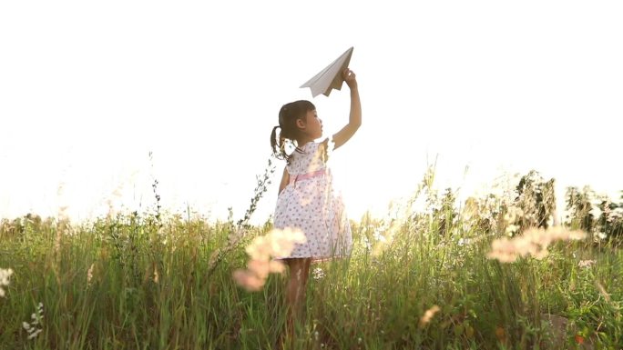 夏天，亚洲女孩和父亲在草地上欢快地放着风筝，自然，慢动作