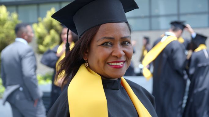 快乐的非裔美国成年女性在博士毕业那天非常开心地看着相机