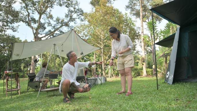 亚裔中国成年夫妇在林地搭建帐篷和营地