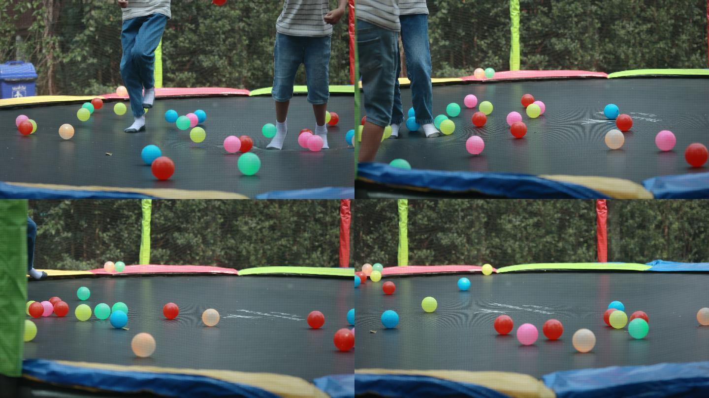 穿袜子的孩子们在蹦床上玩着五颜六色的球。