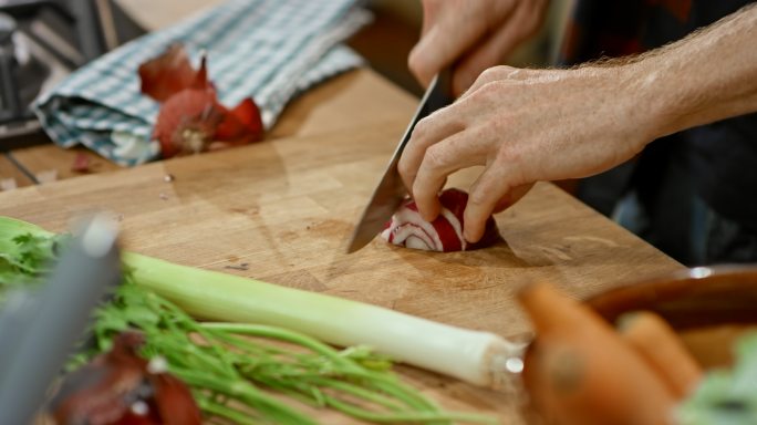 男厨师的双手在厨房的木板上切红洋葱