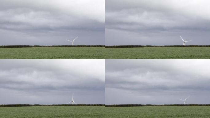 绿色农田地平线上的风力涡轮机与阴云密布的天空形成鲜明对比