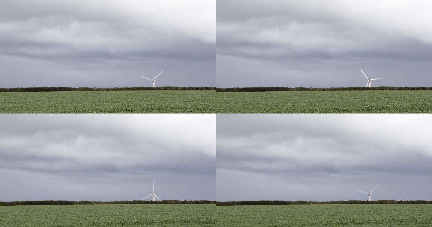 绿色农田地平线上的风力涡轮机与阴云密布的天空形成鲜明对比
