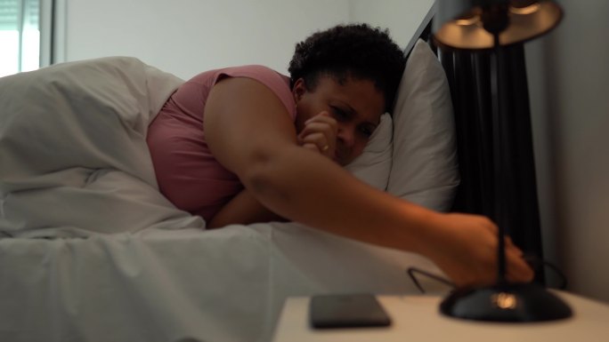 女人在家里床上醒来检查智能手机