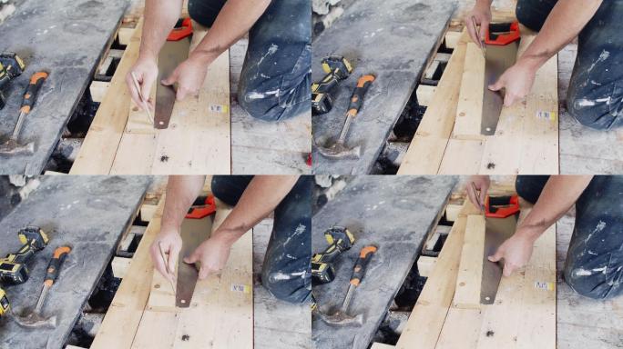 男建筑工人用锯子标记地板