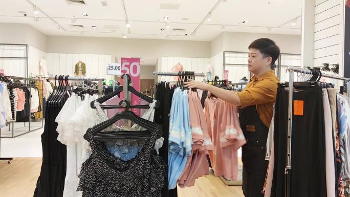 亚洲华人女性精品店服装店店主正在整理服装