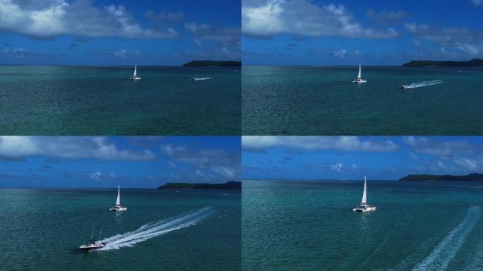 蓝天白云下行驶中的双体帆船和疾驰的快艇
