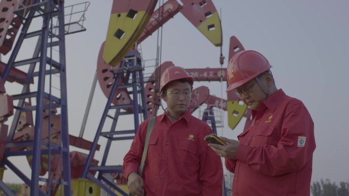 在油井使用智能设备进行检修的石油工人