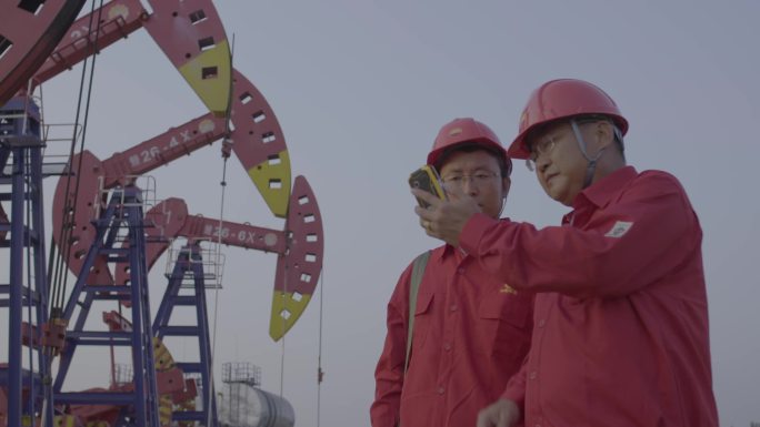 在油井使用智能设备进行检修的石油工人