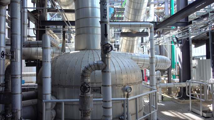 电厂内带保温层的蒸汽金属管道、带标签的量规和阀门的全景图