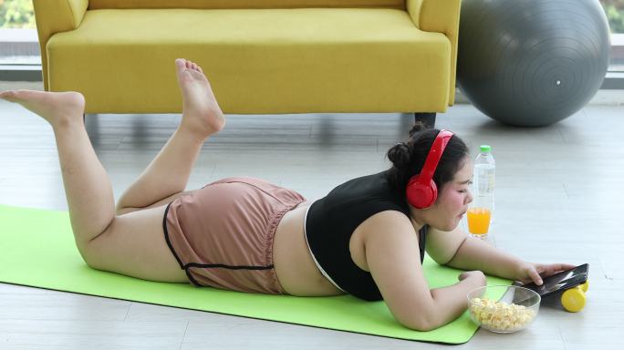 身材高大的女性听音乐，亚洲女孩喜欢在家里的沙发上吃东西，锻炼肥胖女性的减肥理念