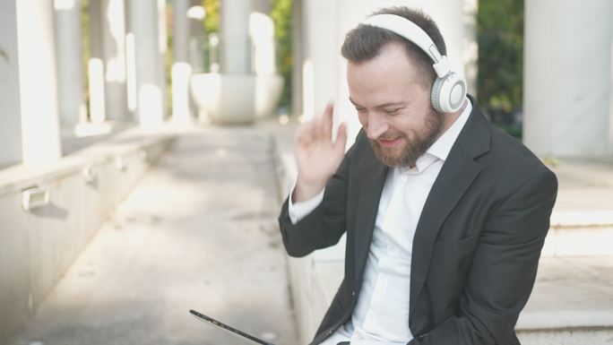 微笑优雅的男性在数字平板电脑和耳机外享受喜爱的音乐氛围