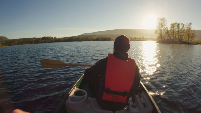 户外冒险：日落时在湖中划独木舟