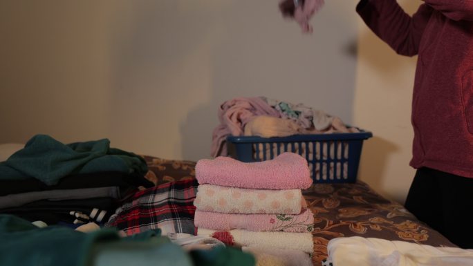 折叠衣物，折叠和整理内衣，毛巾和袜子在洗衣机中清洗，女性在现代卧室整理衣服，女性在篮子里整理衣服房间