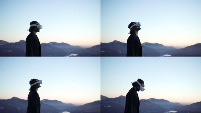 戴着VR虚拟现实护目镜的男子在山中的户外，在夕阳下俯瞰湖面，环顾四周