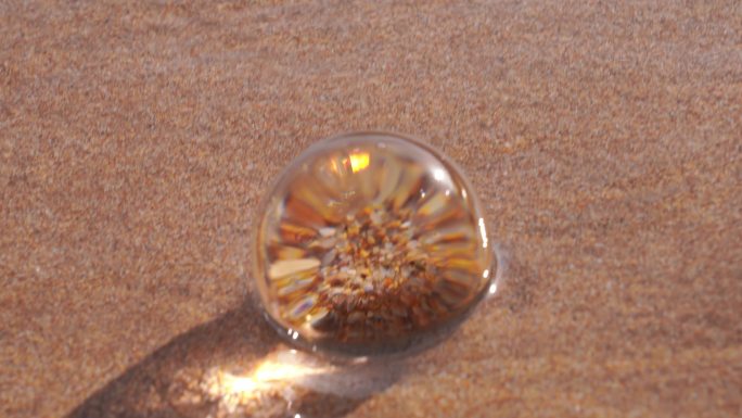 红沙滩上水晶球上的波浪