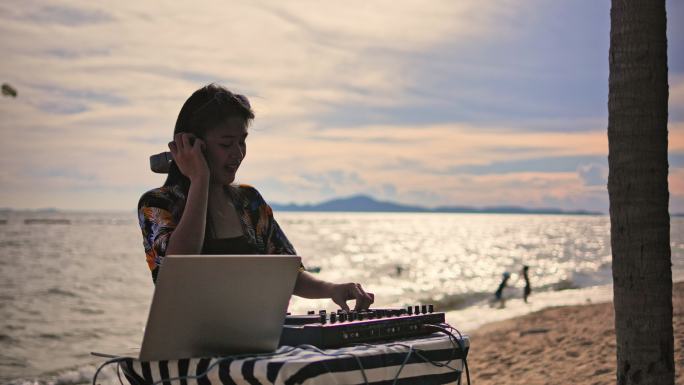 亚洲年轻女子DJ在海滩的转台上演奏音乐。