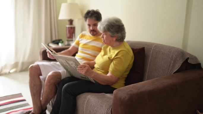 老妇人和她的成年儿子翻阅家庭相册