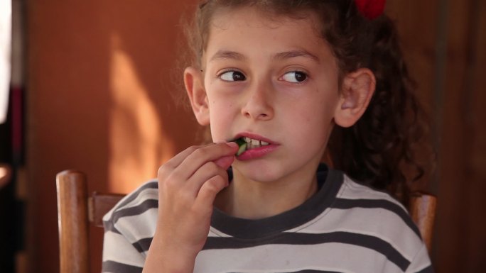 一个吃黄瓜的小女孩的肖像
