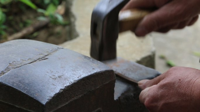 老人手工制作木船用榔头捶打铁钉特写