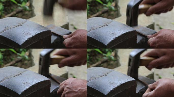 老人手工制作木船用榔头捶打铁钉特写